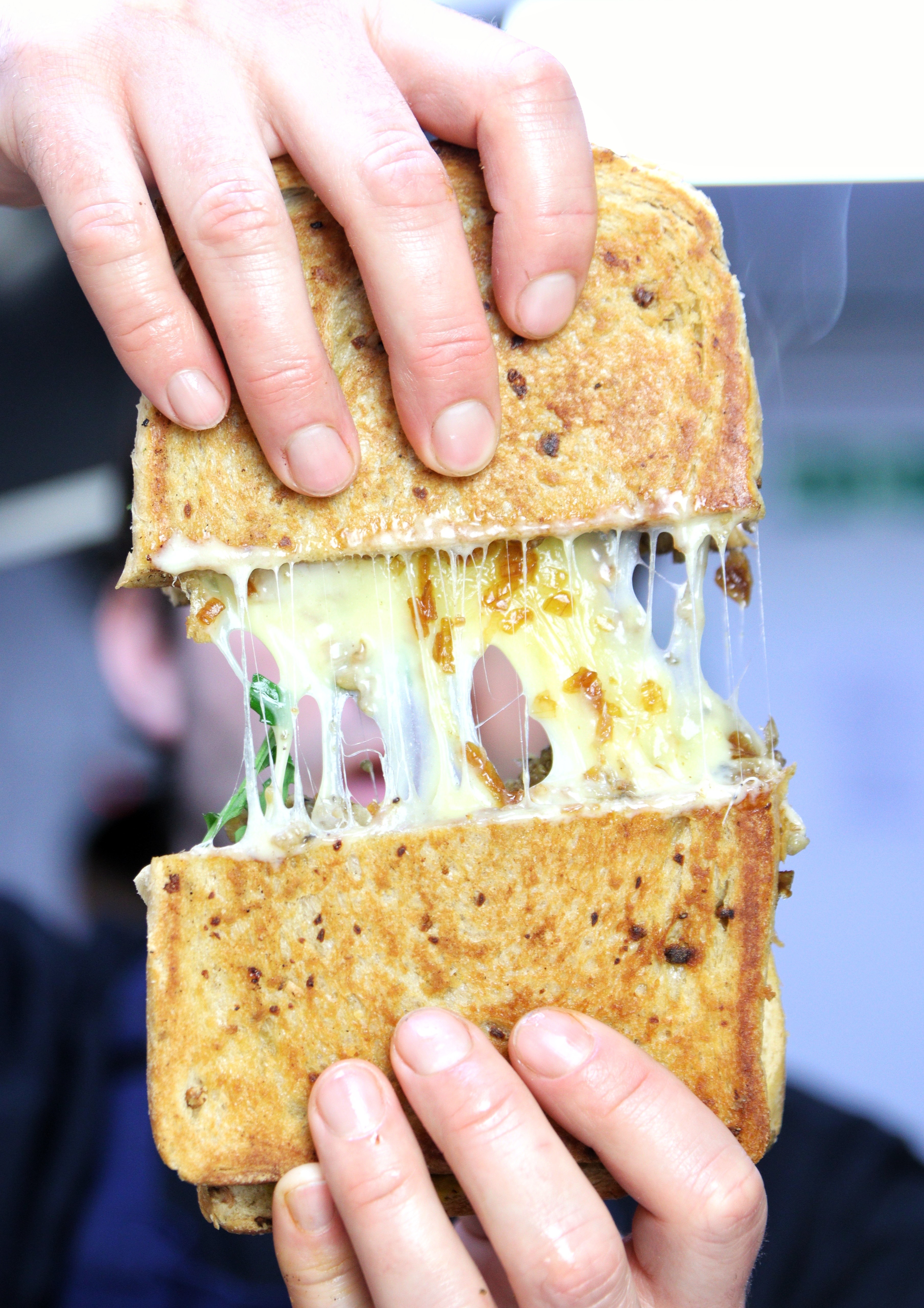 A Deeny's toasty is separated into two, revealing an abundance of cheddar coated ingredients 