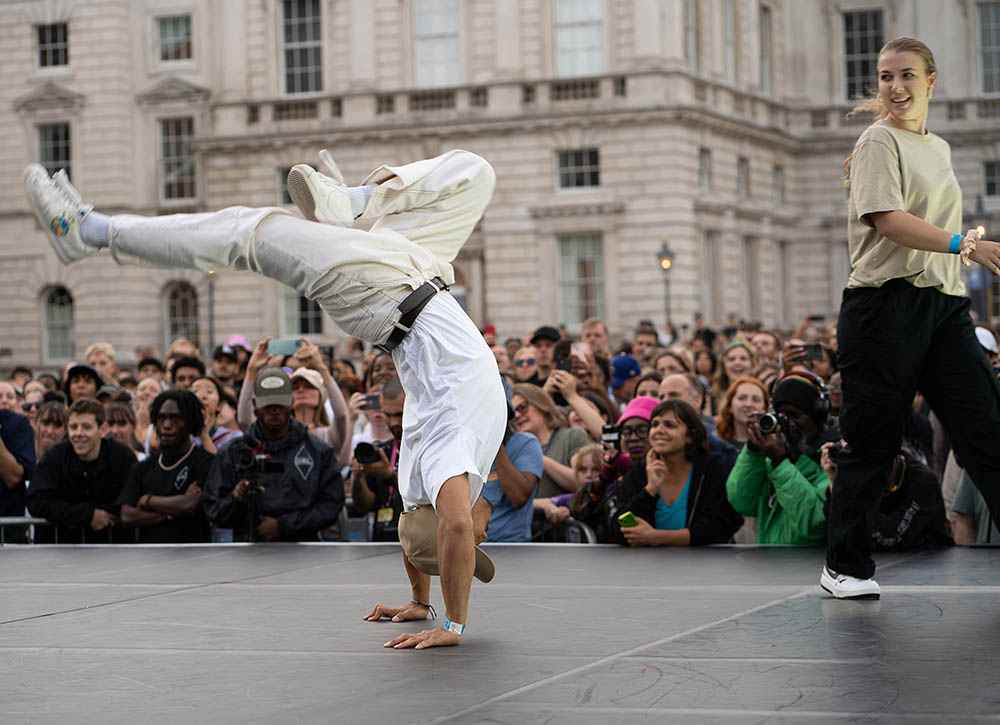 Someone break dancing. They are stood on their hands, with their legs suspended in the air.