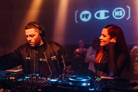 Rinse FM founder Geeneus on the decks with a guest to his right and a crowded audience in the background at a 30th anniversary event