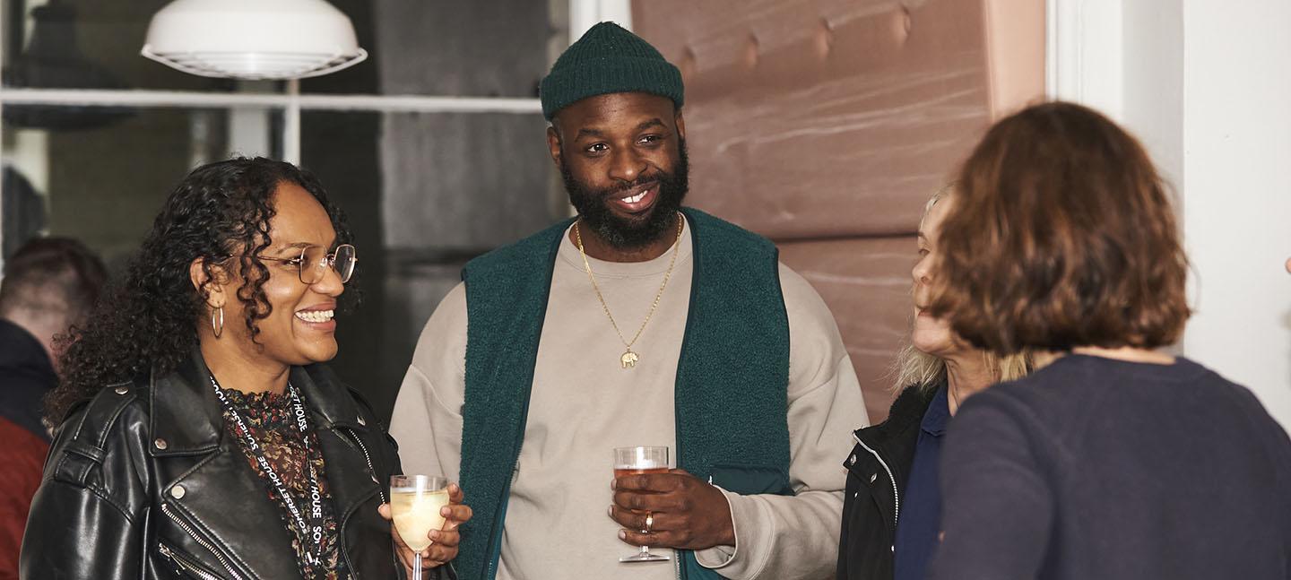 Two people stand holding drinks and smiling at last year's celebration event.